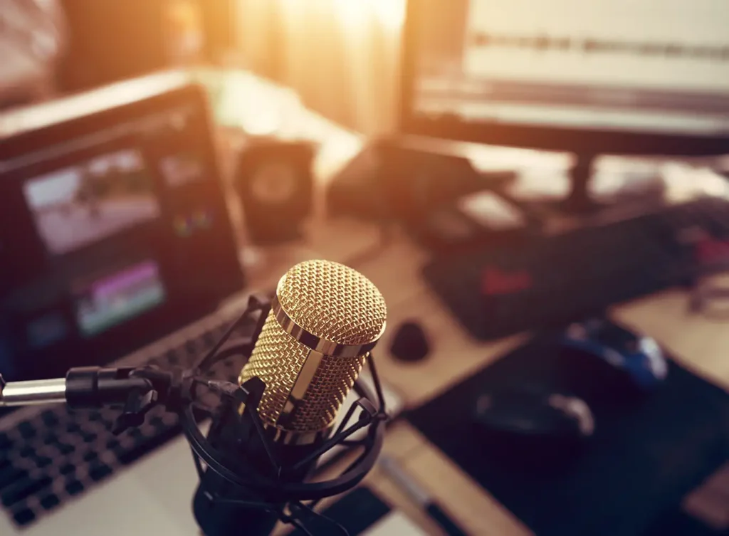 microphone on a boom and a desk with computers running audio and video software